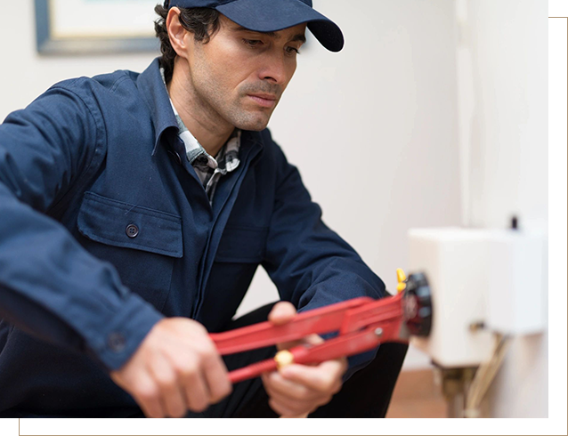 A man in blue jacket holding red pipe wrench.